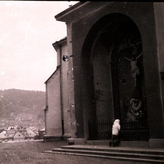 Vintage photo of person near church facade with crucifix.