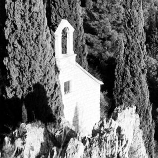 Isolated cliffside chapel in rugged mountainous terrain.