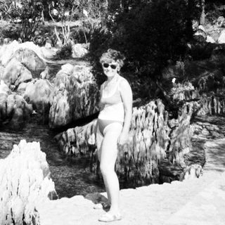 Woman posing by natural rock waterfall.