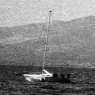 Boats on calm ocean with distant mountains.