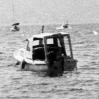 Coastal scene with rocky shore and boats at sea.