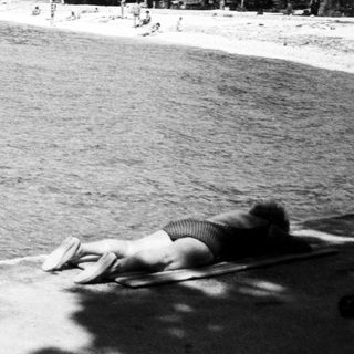 Beach scene with people swimming and relaxing.
