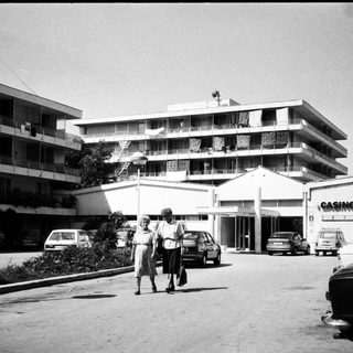 Mid-century motel with casino signage, two people walking outside.