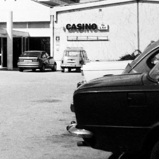 Mid-century motel with casino signage, two people walking outside.