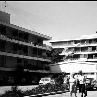 Mid-century motel with casino signage, two people walking outside.