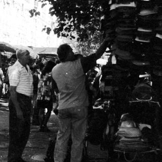 Outdoor market scene with people browsing stalls.