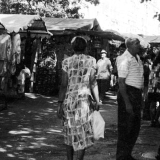 Outdoor market scene with people browsing stalls.
