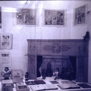 Vintage room display with antique books, prints, and fireplace scene.