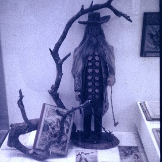 Vintage scarecrow display with books and props.