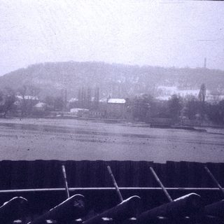 Rural landscape with snow-covered fields and distant village.