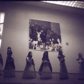 "Black-and-white art exhibit with chess pieces and framed scene."
