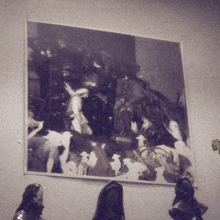 "Black-and-white art exhibit with chess pieces and framed scene."
