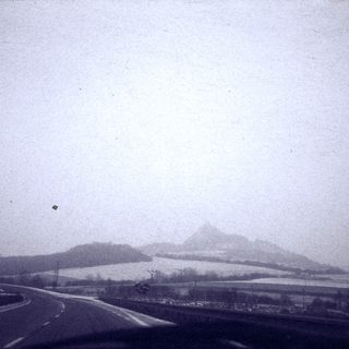 Foggy road with distant snow-covered mountains.