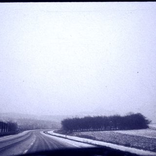 Snowy rural road with light fog.