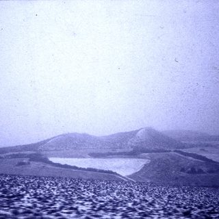 Rural landscape with terraced hills and misty horizon.