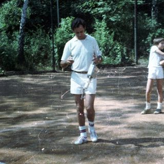 Two people playing tennis on outdoor court.