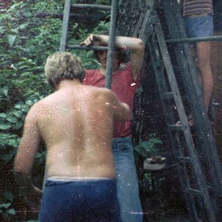 People climbing ladder near waterfall in forest.