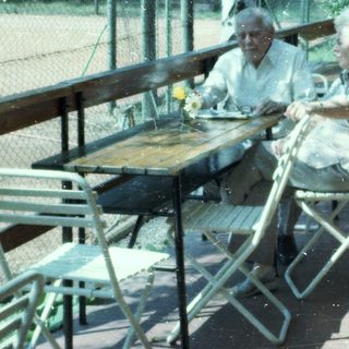 Two elderly people sitting outdoors at a café table.