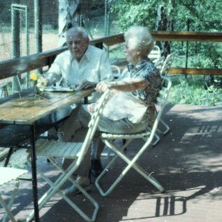 Two elderly people sitting outdoors at a café table.