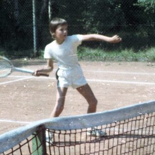 Young man playing tennis on outdoor court.
