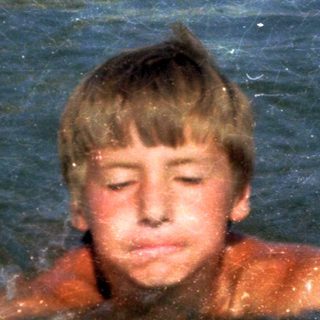 Boy swimming in pool with diving board.