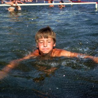 Boy swimming in pool with diving board.
