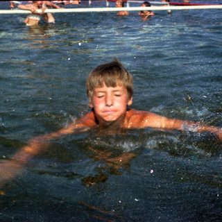 Boy swimming in pool with diving board.
