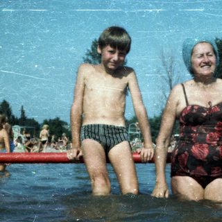 Two people, likely grandmother and grandson, enjoying water together at a pool.
