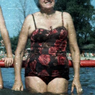 Two people, likely grandmother and grandson, enjoying water together at a pool.