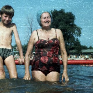 Two people, likely grandmother and grandson, enjoying water together at a pool.