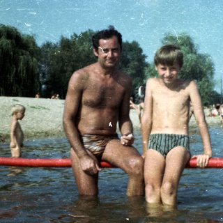 Shallow lake scene with man and boy sitting.
