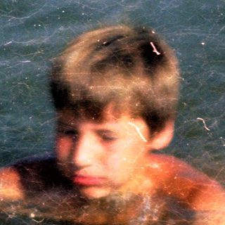 Boy swimming in dark, murky water.
