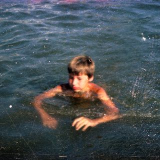 Boy swimming in dark, murky water.