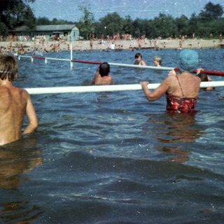 Children playing in a crowded outdoor swimming pool.