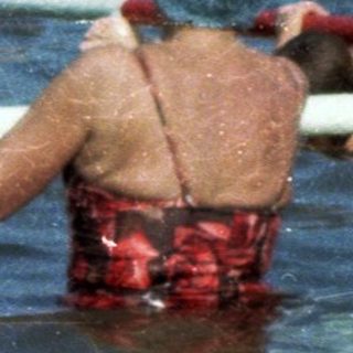 Children playing in a crowded outdoor swimming pool.