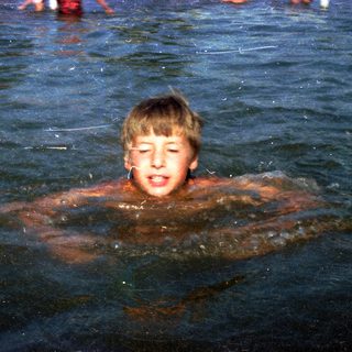 Boy swimming in murky water.