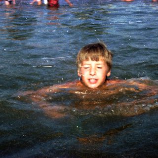 Boy swimming in murky water.