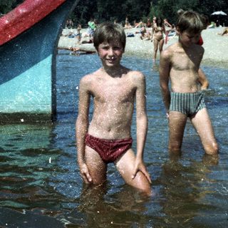 Two boys playing in shallow water at a beach.