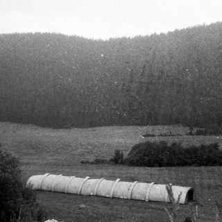 Rural landscape with hay bales and forested hills.