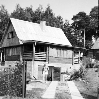 Rural wooden house with person standing near entrance.