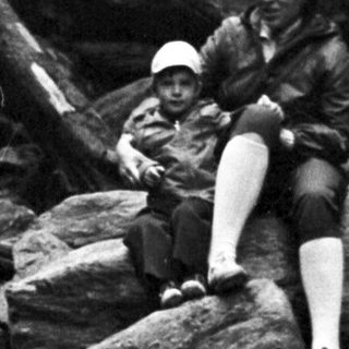 Woman sitting on rocks in forest stream.