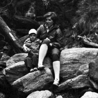 Woman sitting on rocks in forest stream.