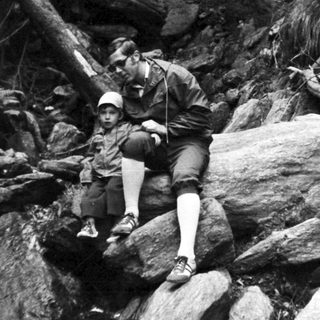 Person rappelling down rocky cliff face.