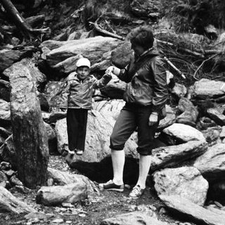 Two people hiking through rocky stream terrain.