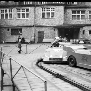 Mini race cars on a track near historic building.
