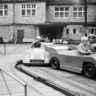 Mini race cars on a track near historic building.