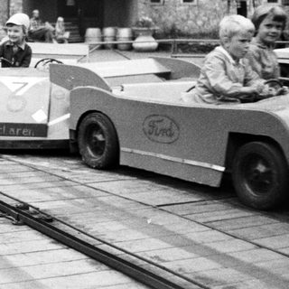 Mini race cars on a track near historic building.