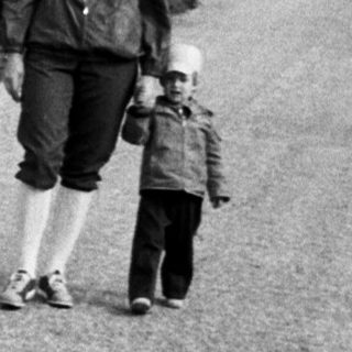 Two adults and child walking on rural road.