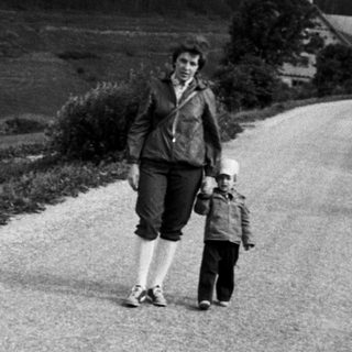 Two adults and child walking on rural road.