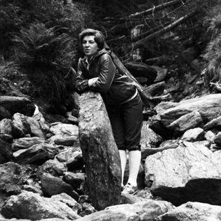 Person hiking through rocky forest terrain.